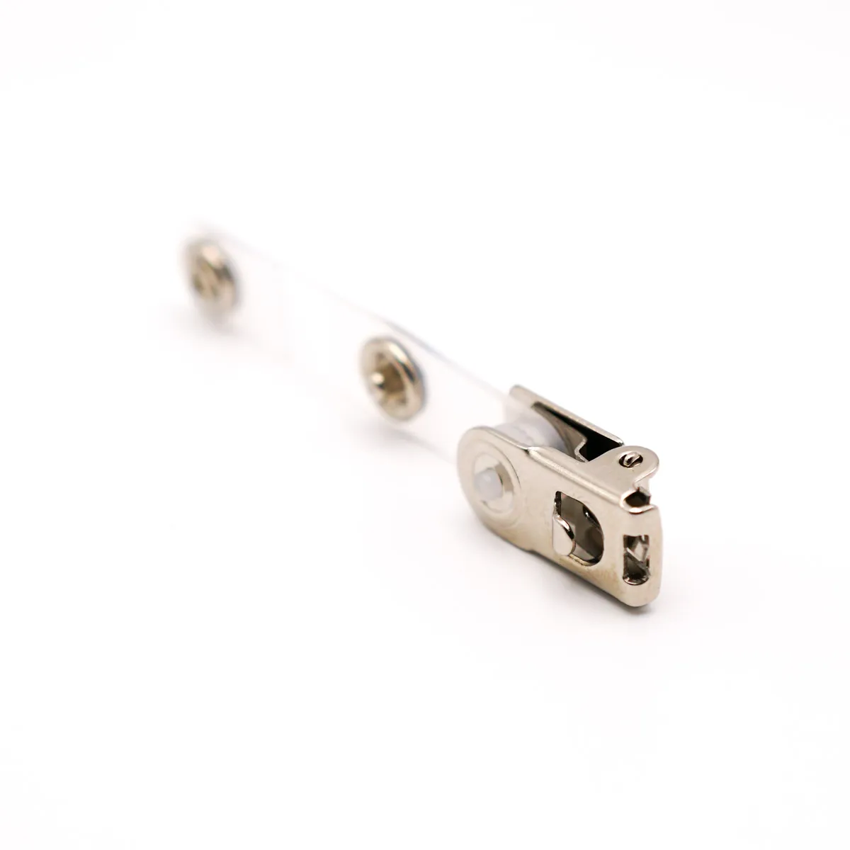Nahaufnahme eines silbernen Premium-Ausweisclips aus Metall auf weißem Hintergrund. Die Ansicht zeigt die flache Oberseite des Metallclips mit seinen Ausstanzungen und der stabilen Nietenverbindung im Vordergrund, während die transparente PVC-Lasche mit…