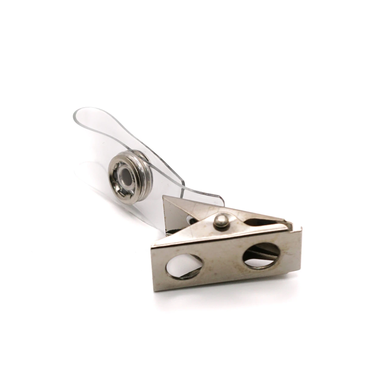 Ein silberner Krokodilclip aus Metall auf weißem Hintergrund mit einer geschlauften, transparenten Kunststoff-Lasche aus PVC. Der Druckknopf aus Metall zur Befestigung von Namensschildern und Ausweishüllen ist gut sichtbar.