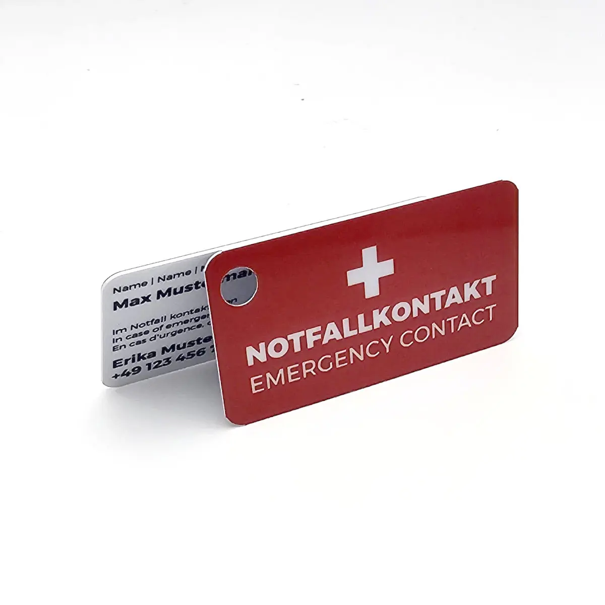 Zwei kleine Notfallkarten mit Lochstanzung auf weissem Grund. Die vordere Karte ist rot mit weissem Kreuz sowie der Aufschrift Notfallkontakt, dahinter ist eine weisse Karte mit Beispieldaten für Name und Telefonnummer sichtbar.