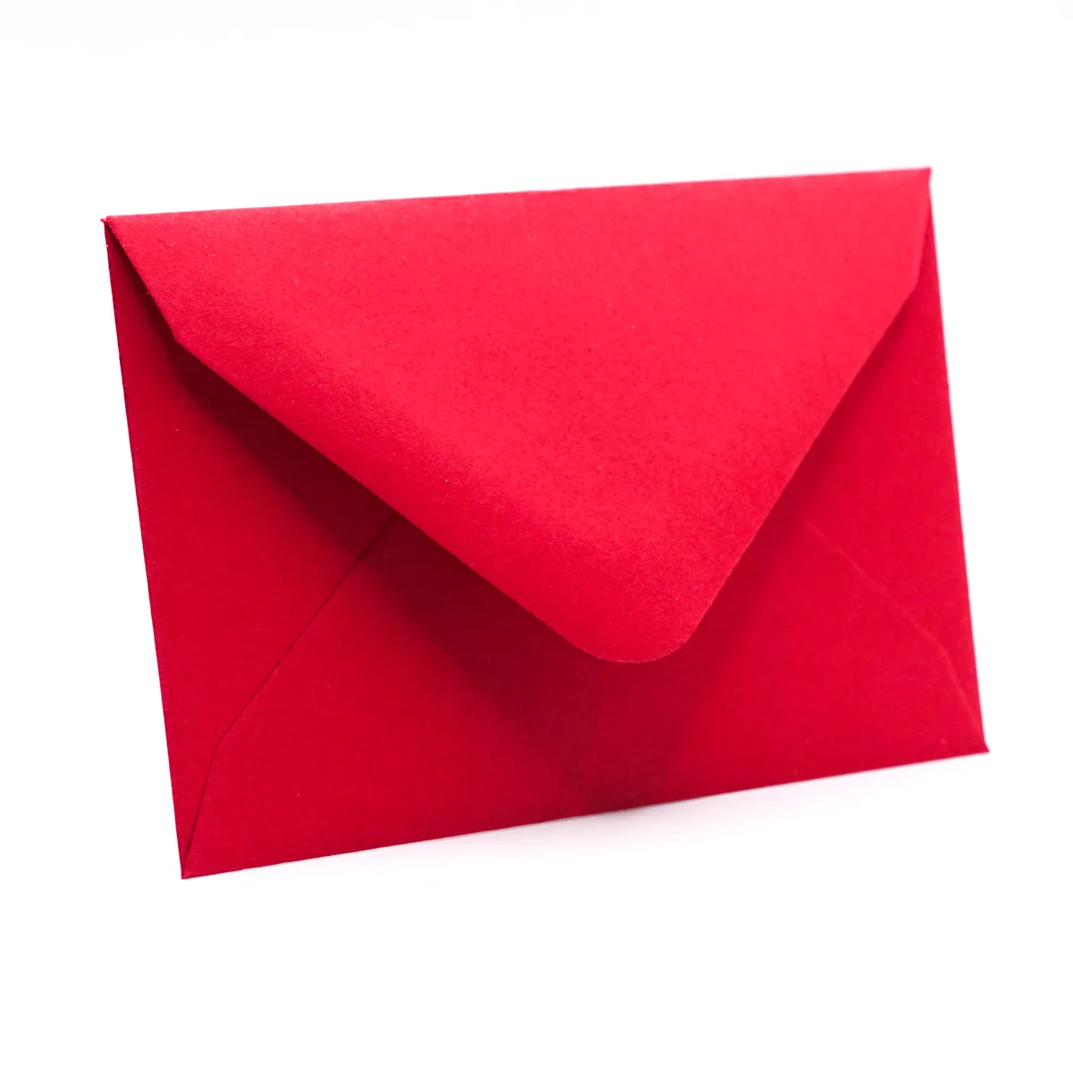 Ein einzelner, geschlossener roter Briefumschlag aus mattem Papier auf rein weißem Hintergrund. Der Umschlag steht leicht angewinkelt im Querformat und zeigt seine Rückseite mit spitz zulaufender, dre