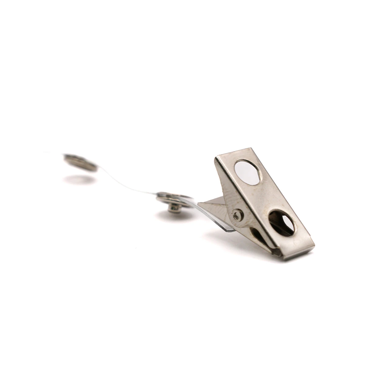 Ein silberner Metall-Krokodilclip auf weißem Hintergrund mit leicht geöffneter, transparenter PVC-Lasche und Druckknopf zur Befestigung von Kartenhaltern oder Ausweisen. Der Clip ist im Vordergrund platziert, während das transparente Band nach hinten aus…