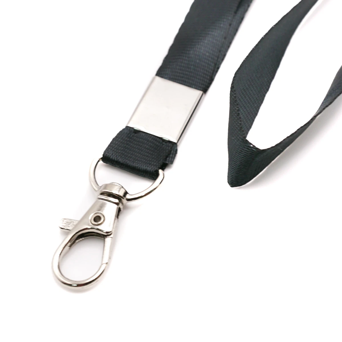 Nahaufnahme des flachen schwarzen Schlüsselbands mit glänzendem Metallkarabiner und Klemme auf weissem Hintergrund.