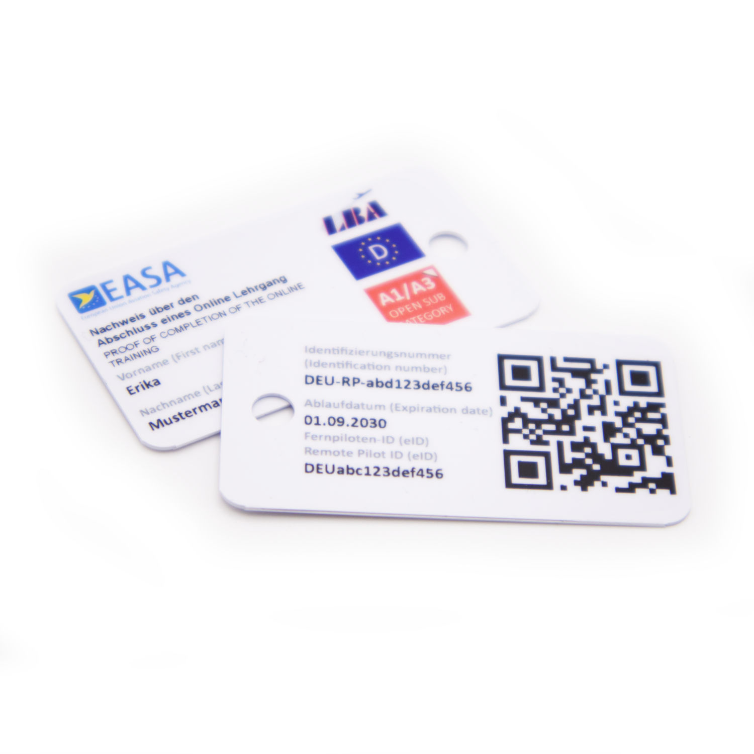 Zwei weisse Minikarten für den EU-Drohnenführerschein vor weissem Hintergrund. Eine Karte zeigt die Vorderseite mit EASA-Logo und Kategorieaufdruck, die andere die Rückseite mit QR-Code und Pilotendaten; beide sind mit einem Rundloch versehen.