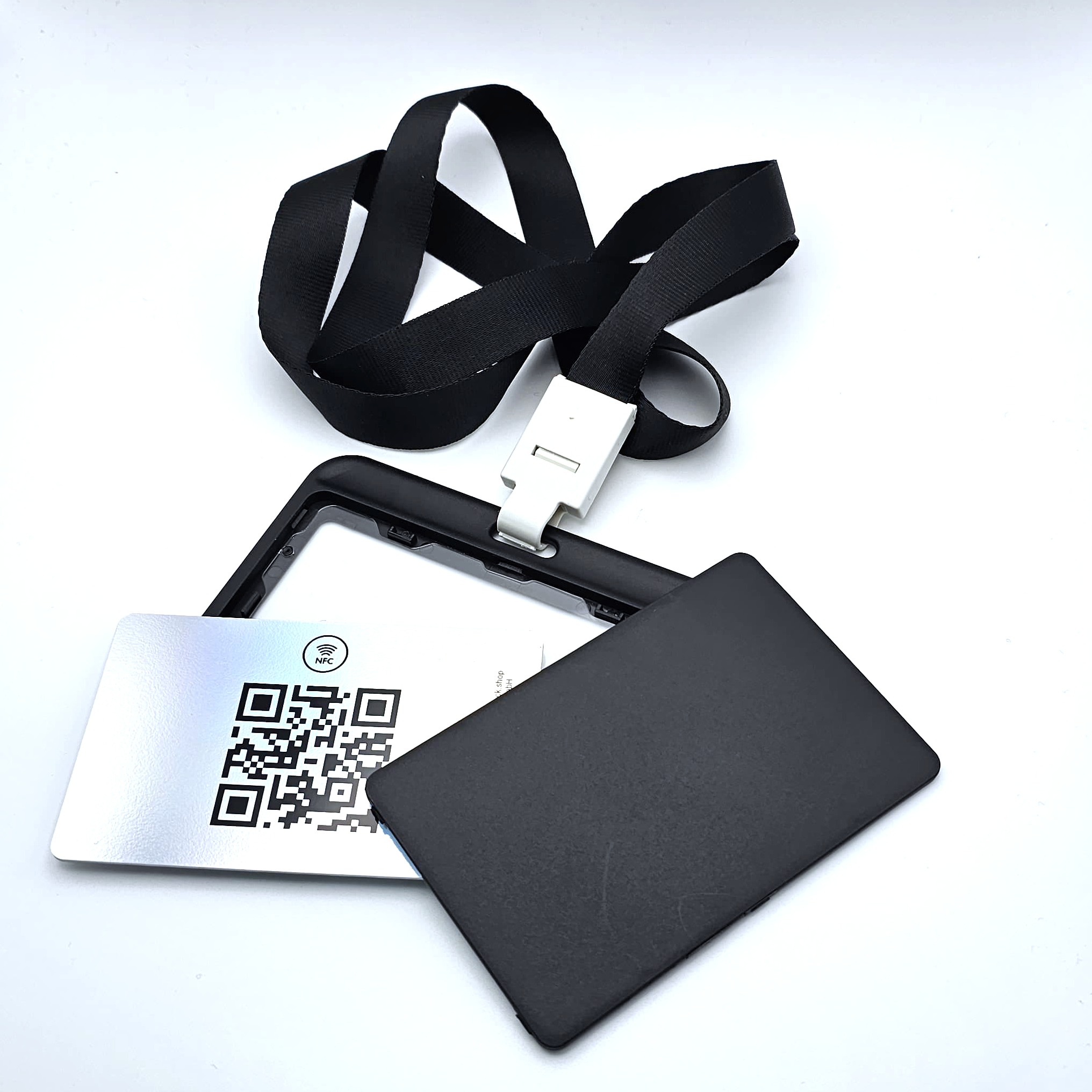 Ein geöffneter schwarzer Kunststoff-Ausweishalter im Querformat mit schwarzem Lanyard und weißem Befestigungsclip auf weißem Hintergrund.